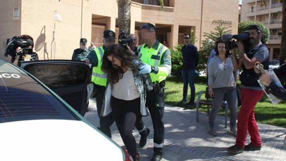 Dos guardias civiles trasladan a la detenida a un vehículo del Destacamento de Tráfico después de que declarara en el juzgado.