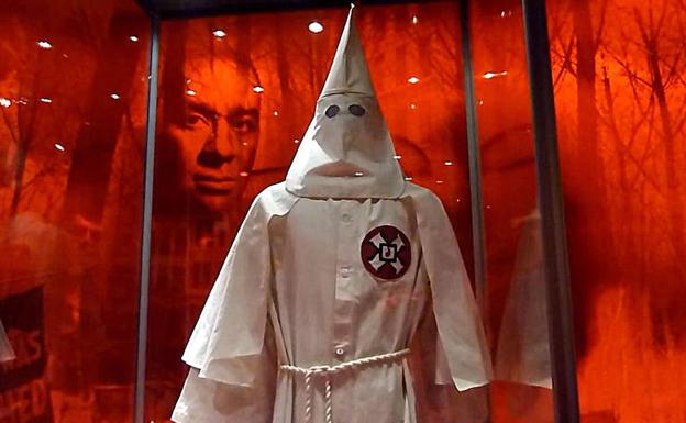 Imagen de un afroamericano detrás de la indumentaria de un miembro del Ku Klux Klan. 
