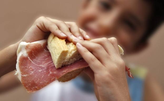 Un niño comiendo un bocadillo.
