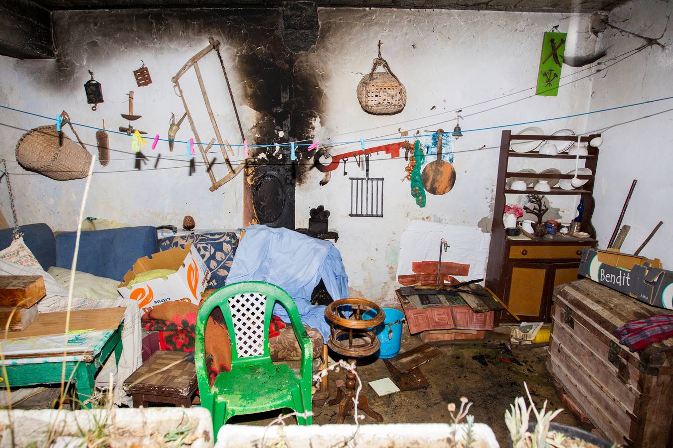 Imagen del exterior de la casa de Josefa Lujua, en concreto del cobertizo de la parte lateral, con rastros del fuego en el viejo sofá y la pared. 
