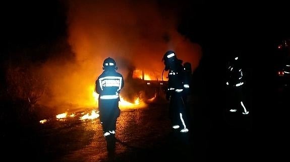 Bomberos del 112 extinguen uno de los coches incendiados esta noche.