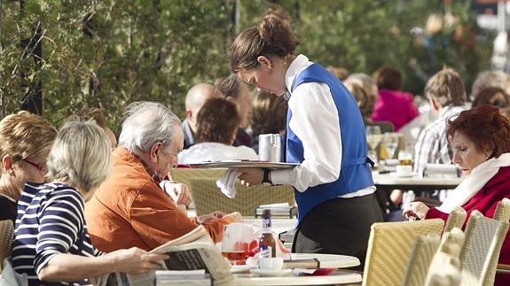 Una camarera atiende una mesa en una terrza de Santander.