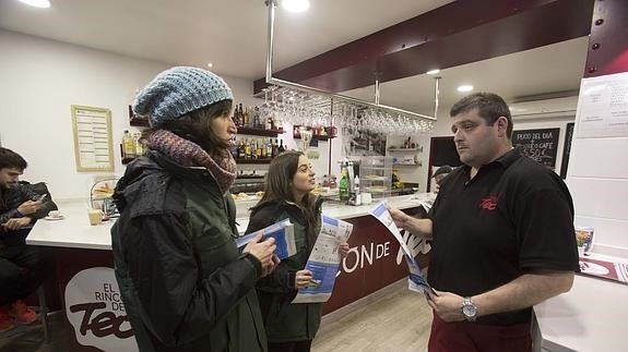 Nerea y Carmen, dos de las informadoras, explican los puntos básicos de la campaña en ‘El rincón de Teo’, un bar de La Porticada.