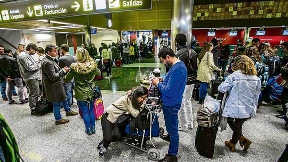 Los pasajeros del vuelo cancelado con destino a Roma hacen cola en la oficina de Ryanair para presentar reclamaciones