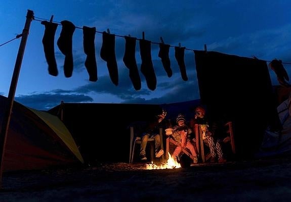 Unos niños se calientan al lado del fuego cuando llega la noche al campamento de Idomeni.