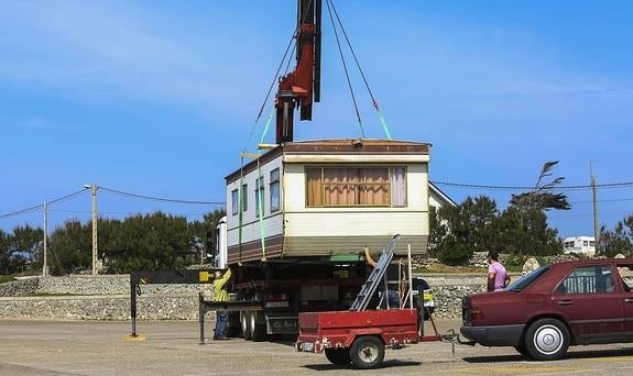 Los propietarios de un módulo de vivienda prefabricada la retiran, ayer mismo, de una de las parcelas ocupadas en Corbanera 