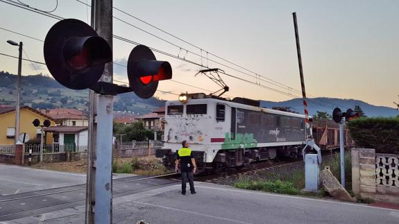 El mercancías llegó al paso con las barreras alzadas y el policía regulando el tráfico. 