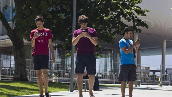 Tres jóvenes recorren los jardines de Pereda buscando nuevos Pokémon con sus móviles.