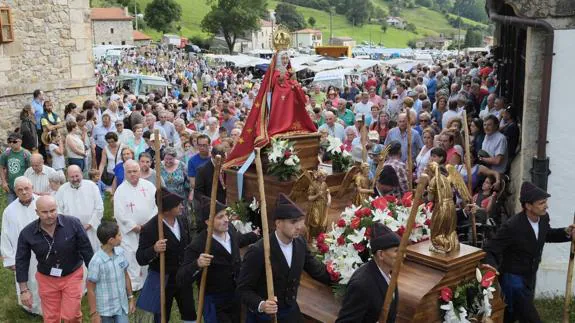 Los cofrades transportan la imagen de la Virgen, seguidos de cientos de fieles. 