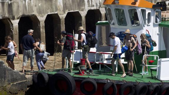 Un grupo de excursionistas se baja de la lancha que llega de Pedreña.