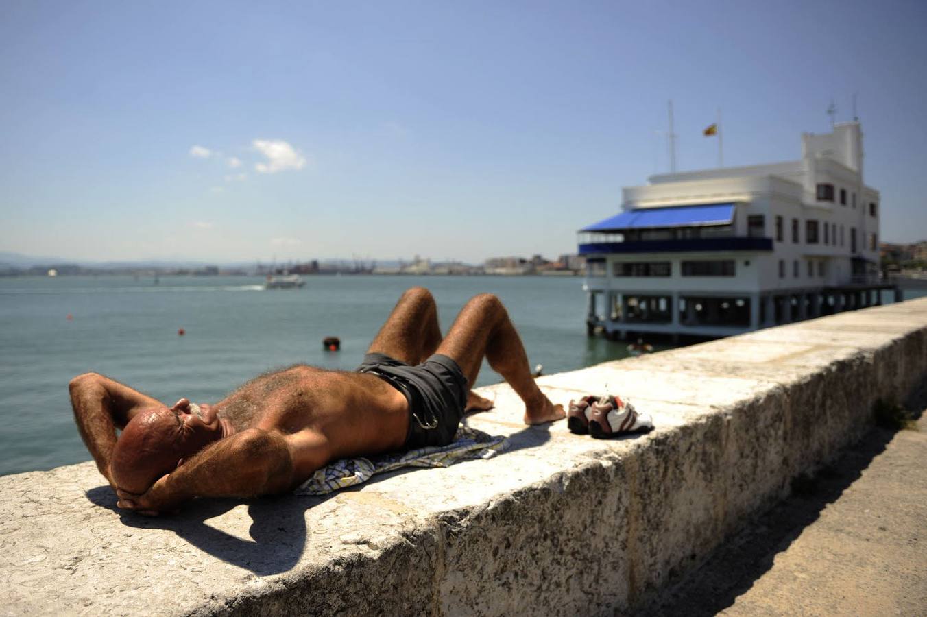 Un hombre toma el sol en el espigón de Puertochico, en Santander