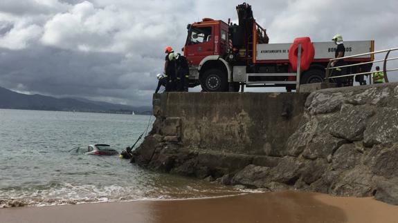 Los bomberos, ayudados por los buzos, rescatan el coche del agua. 