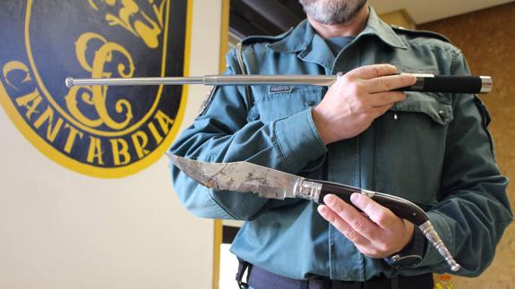 Un agente sujeta dos de las armas intervenidas en las redadas.