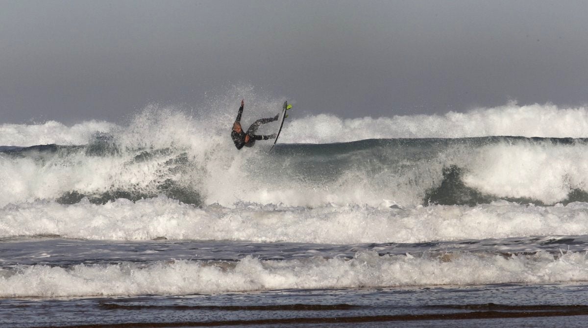 El jóven surfista cántabro Miguel Betegón realiza una llamativa maniobra sobre su tabla en la playa de Canallave.