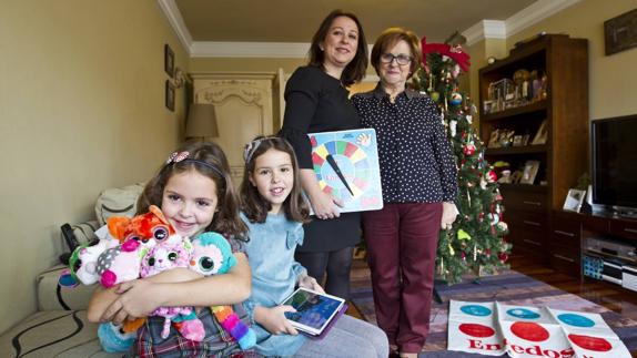 Inés Linares del Río sostiene parte de su colección de ‘ojitos’, y su hermana Alba, una tableta. Detrás, Amaya del Río con la ruleta del juego ‘Enredos’, y su madre, María Ángeles Cotera. La noche de Reyes prepararán unas viandas para los magos y sus camellos.