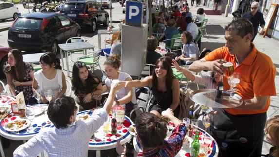 Un camarero atiende a unos clientes en una terraza de la calle Calderón de la Barca de Santander.