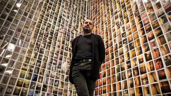 Oriol Vilanova, uno de los exponentes de la muestra colectiva, posa frente a uno de sus murales con las postales que colecciona desde su época de estudiante.