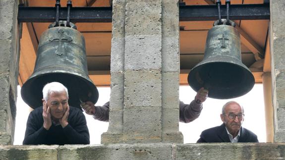 Ruidosa tradición. Dos hombres se asoman por el campanario de San Pedro de Bernueces, en Asturias, mientras tañen las campanas.