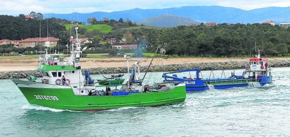 Un pesquero navega por la zona en la que se eliminará la roca del fondo, junto a una draga durante la retirada de arena habitual. 