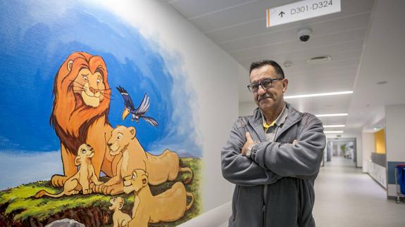 Manuel Fuentes, junto al mural de la familia del Rey León que preside el pasillo de la planta de Pediatría, en la torre D de Valdecilla