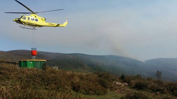 El helicóptero del 112 realizando una carga de agua en Silió (Molledo).