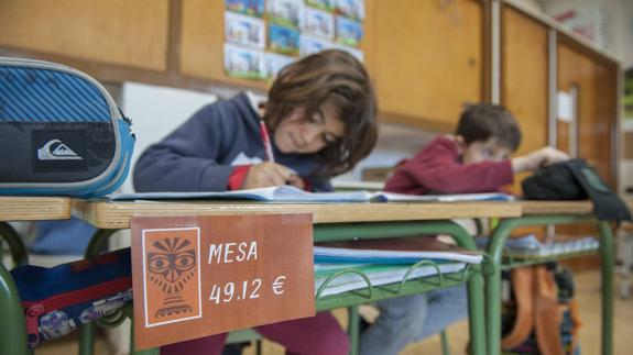 Un escolar escribe sobre una mesa que ha sido etiquetada para que los niños conozcan su valor.