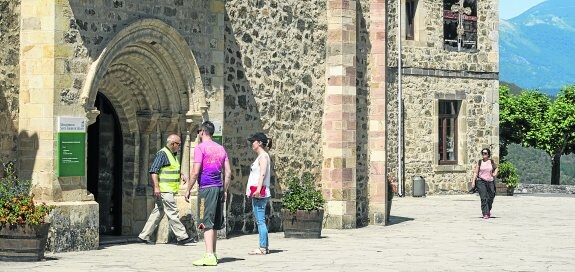 Dos turistas se disponen en la mañana de ayer a cruzar la Puerta del Perdón del monasterio de Santo Toribio de Liébana. 