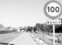 Cartel limitador de velocidad. Al fondo, el pórtico que sustenta el radar que detectó al infractor. / SANE
