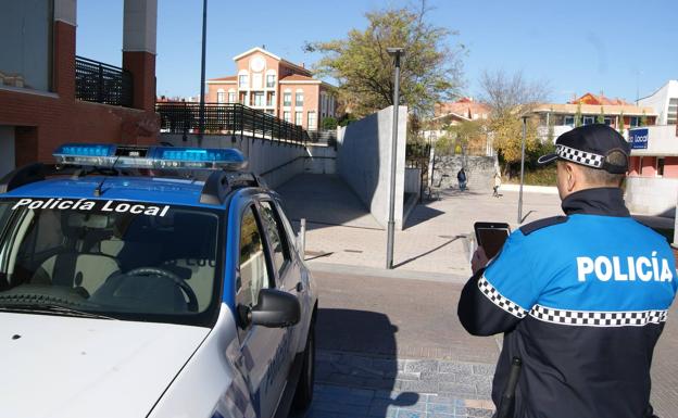 Un agente de la Policía Local de Arroyo junto al coche patrulla en la plaza de España de La Flecha. 