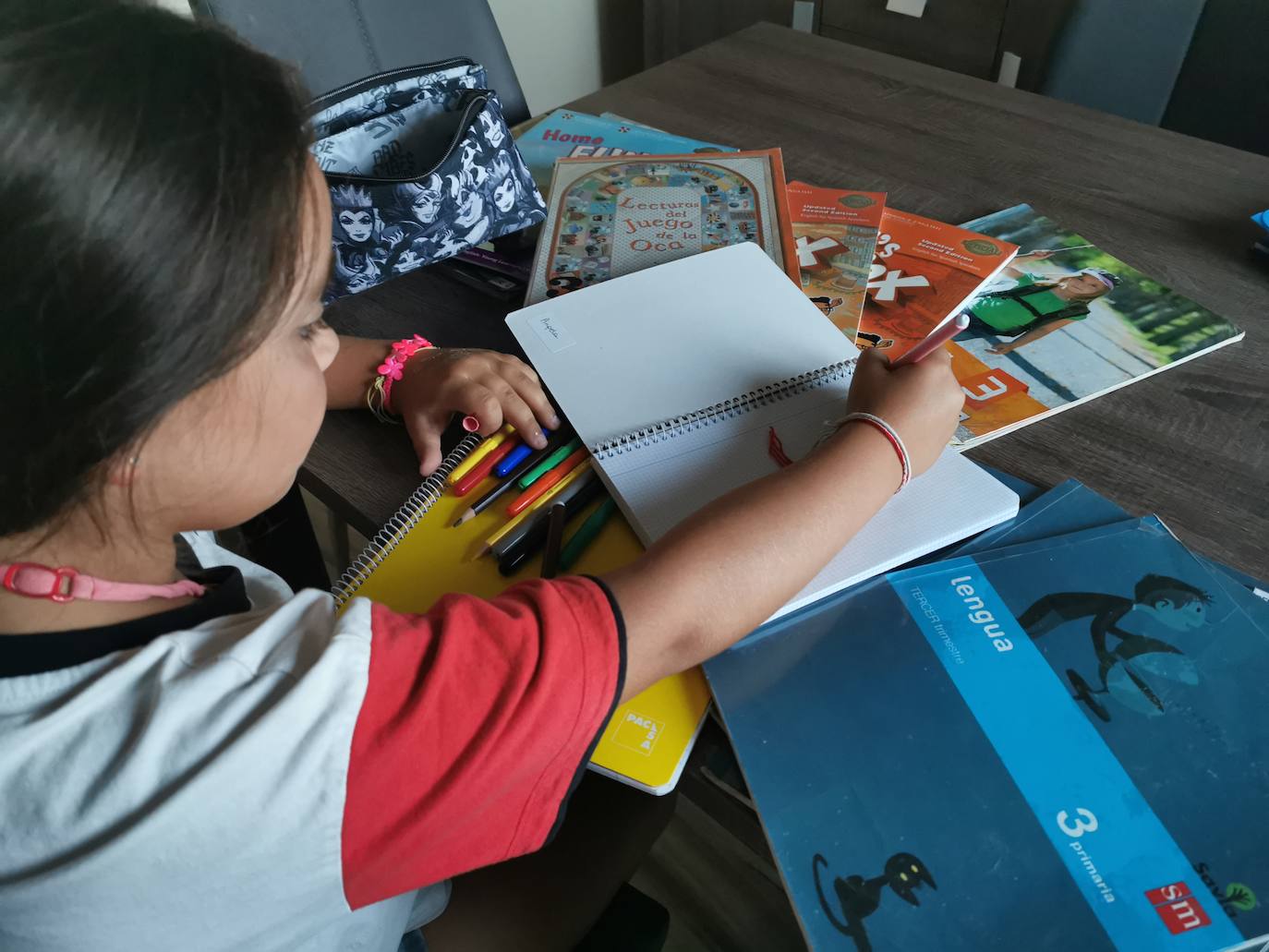 Una niña revisa sus libros y material escolar para el próximo curso 