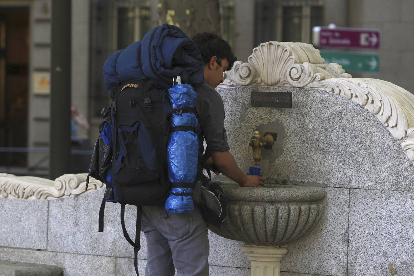 Un hombre rellena su botella de agua en una fuente frente al Paseo de la Castellana en Madrid, en una jornada con temperaturas de hasta 38 grados en plena ola de calor.