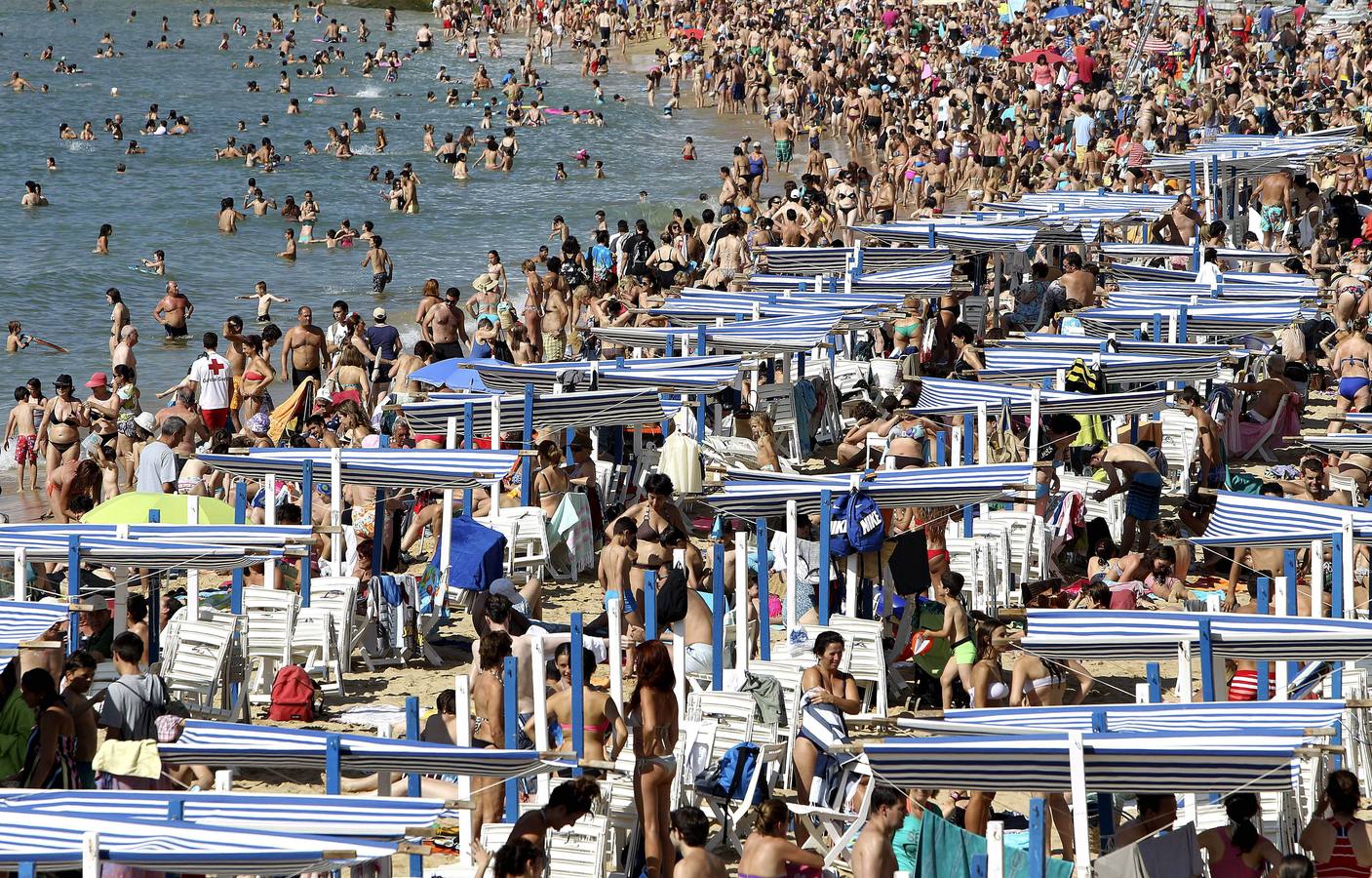 Gran número de personas se han acercado a la playa de La Concha de San Sebastián, para aprovechar las altas temperaturas registradas hoy en la ciudad.