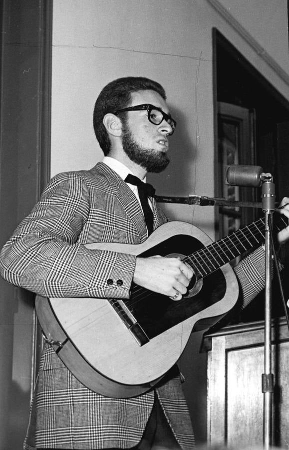 Cantando y tocando una guitarra.