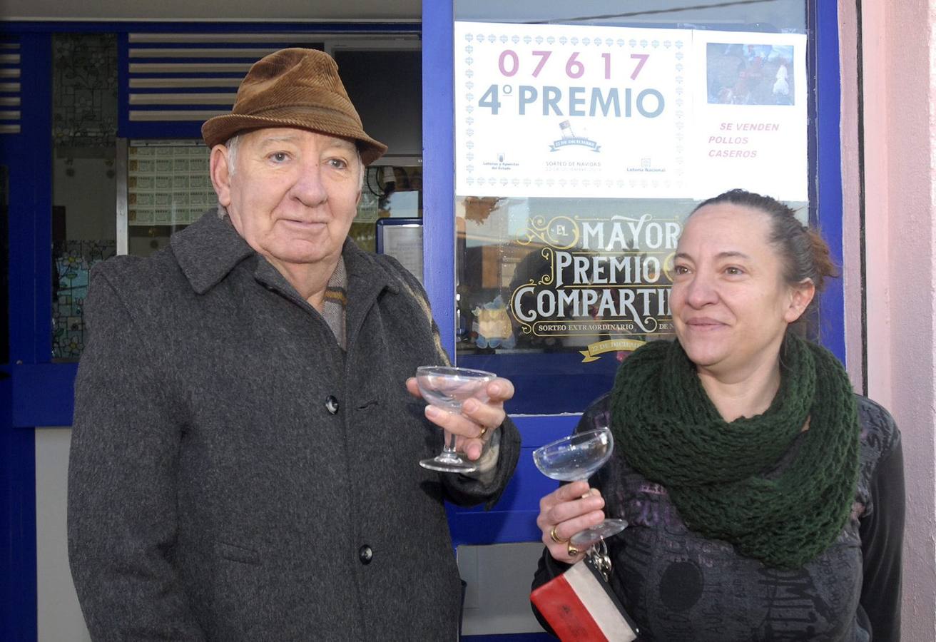 Armunia (León). Loli Martínez (d), hermana de la titular de la administración número 17 ubicada en el número 25 de la calle General Sanjurjo, en Armunia (León), que ha vendido treinta series del 07617, agraciado con uno de los dos cuartos premios dotados con 200.000 euros a la serie (20.000 euros al décimo), y que fueron adquiridas íntegramente por una residencia de ancianos de la localidad, lo celebra con cava en la puerta de su negocio.