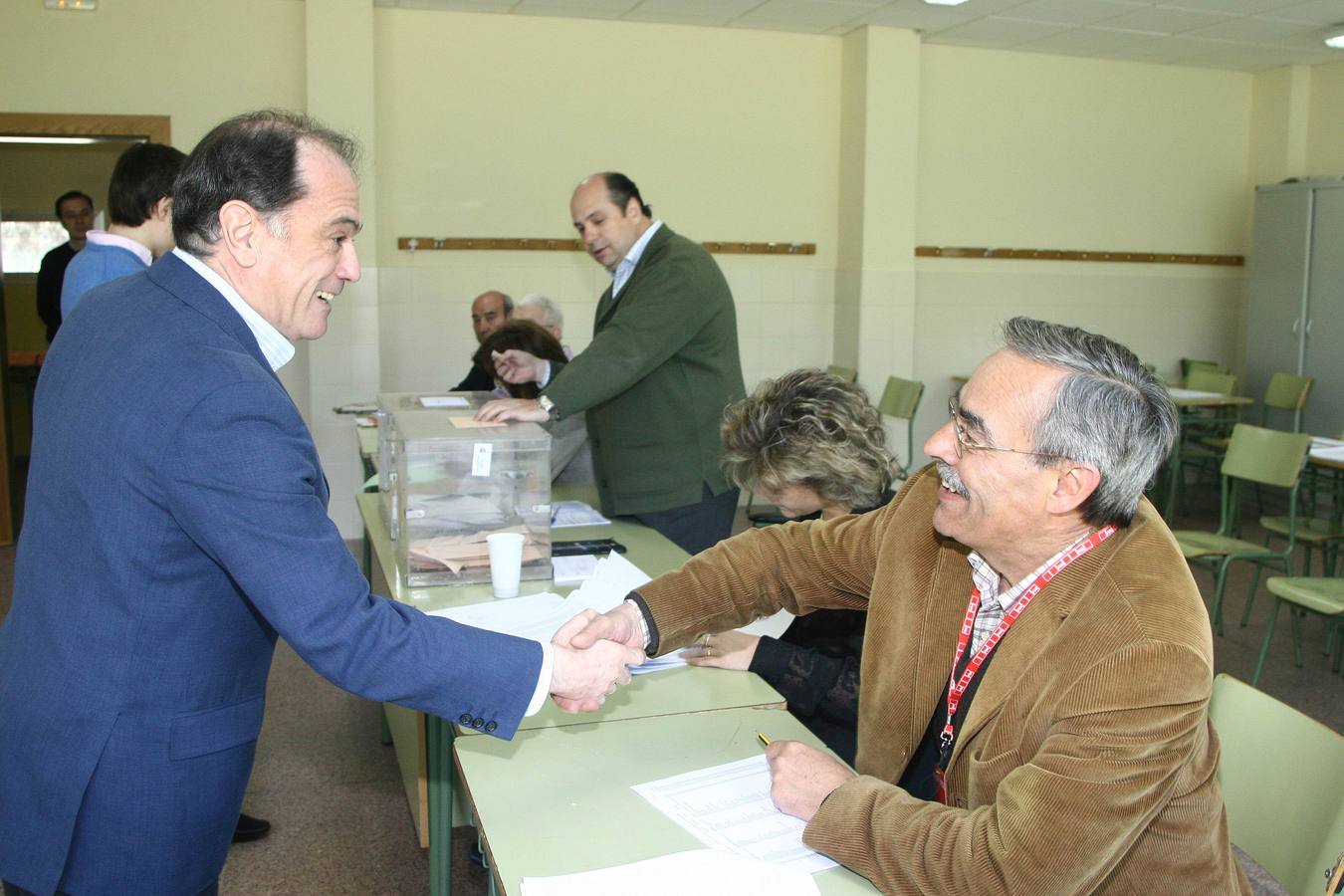 El candidato número uno a las Cortes del PP en Valladolid, Tomás Villanueva, saluda al socialista Ángel Velasco que forma parte de la mesa electoral donde votó el candidato del PP, en Valladolid.