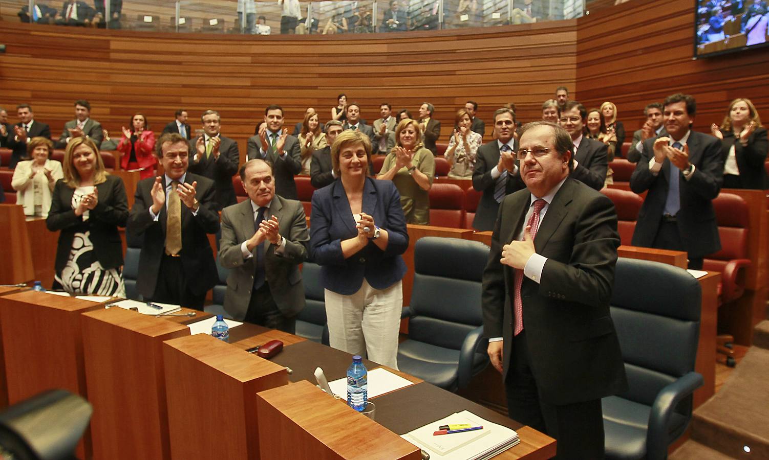 El reelegido presidente de la Junta de Castilla y León, Juan Vicente Herrera (d), recibe los aplausos de los miembros de su partido tras la votación celebrada en el debate de investidura.