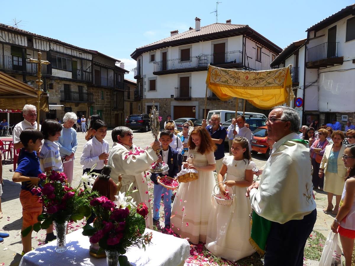 Un momento de la celebración en Sequeros, justo cuando los niños de Primera Comunión echan pétalos a la Custodia sujetada por el párroco.