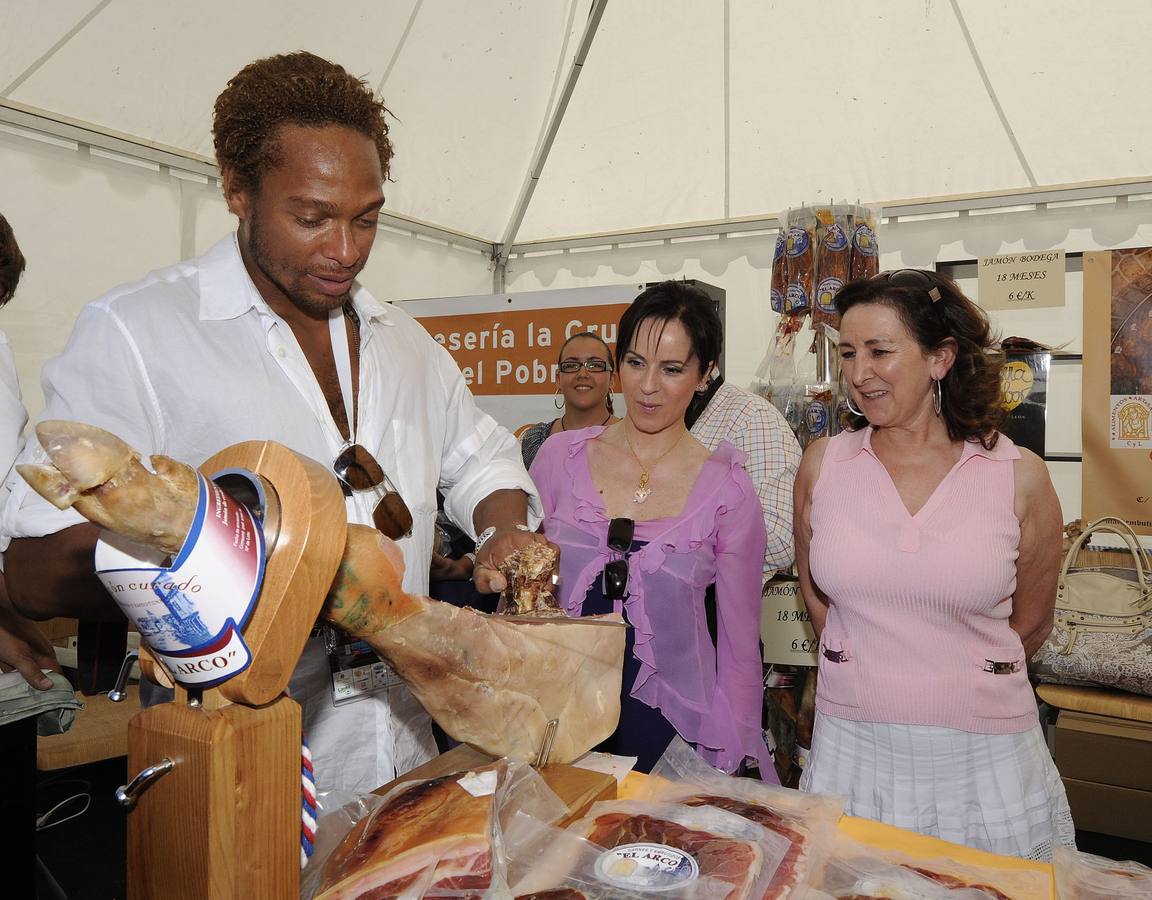 La consejera, Silvia Clemente (c), y el actor, Gary Dourdan, imagen de la campaña de la Junta 'Tierra de Sabor', en uno de los puestos con productos que han acompañado los IV Internacionales Ciudad de Valladolid. 05/07/2009