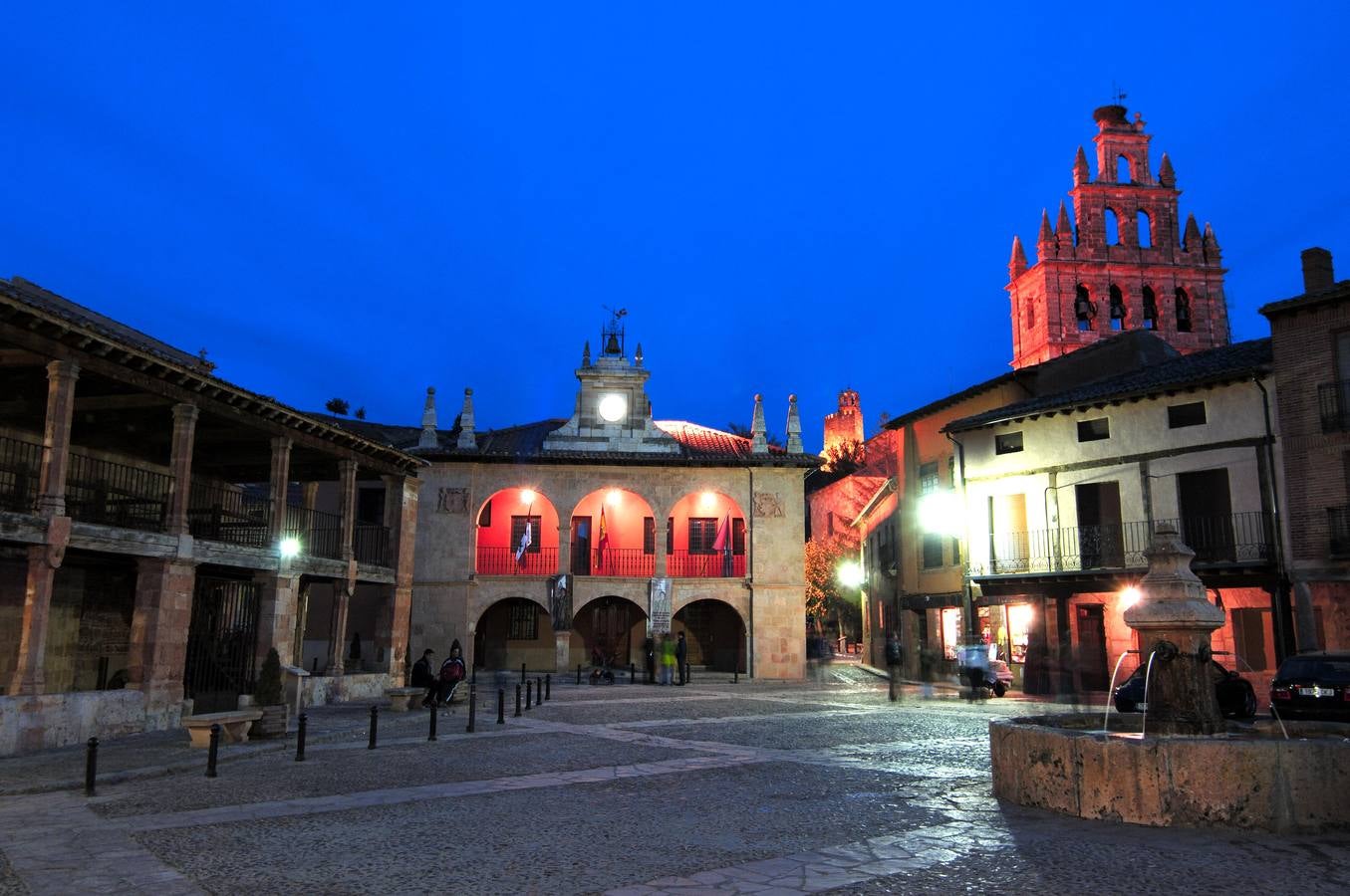 Ayllón (Segovia). Al nordeste de la provincia de Segovia, limitando con Soria, Guadalajara y Burgos, se encuentra la Villa de Ayllón, junto a la Sierra que lleva su mismo nombre, y responsable del color característico de esta zona. De especial interés son su Plaza Mayor, sustentada sobre soportales de madera; el Ayuntamiento, antiguo Palacio de Los Marqueses de Villena; sus edificios civiles como el Palacio del Obispo del Vellosillo, el de Los Contreras o el de Eugenia de Montijo o sus edificios religiosos como la antigua iglesia románica de San Miguel o la Iglesia de Santa María la Mayor.