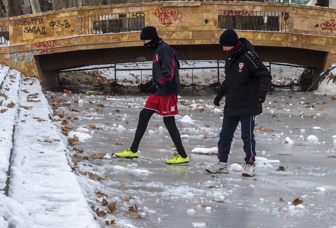 Dos jóvenes cruzan un lago congelado en un parque de Skopje, Macedonia.