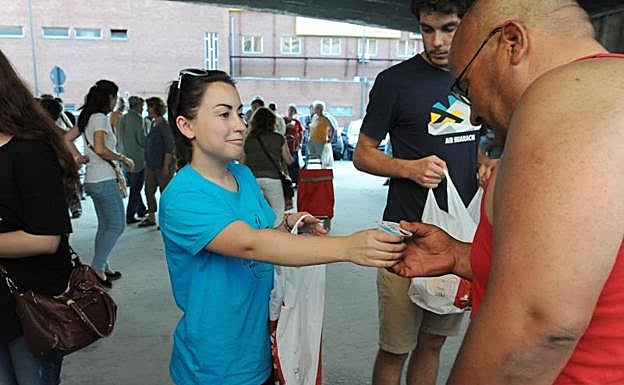 Una estudiante entrega alimentos a una persona que acude a la convocatoria de Asalvo. 