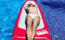 Cristina Rodríguez, al sol, sobre una tabla de surf en la piscina. 