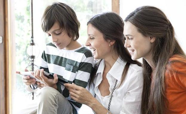 Un niño observa las redes sociales con su madre y hermana.