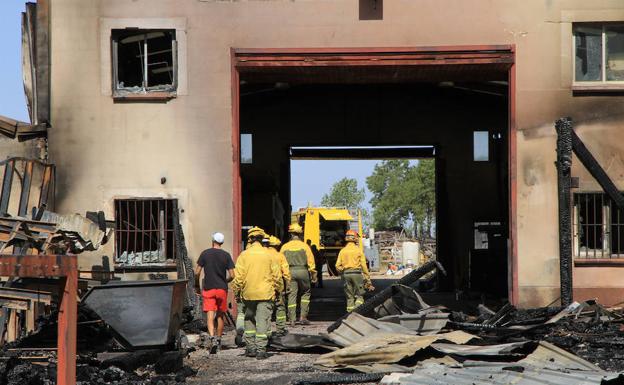 Efectivos de extinción de incendios comprueban una de las naves arrasadas por el incendio en Valsaín. 