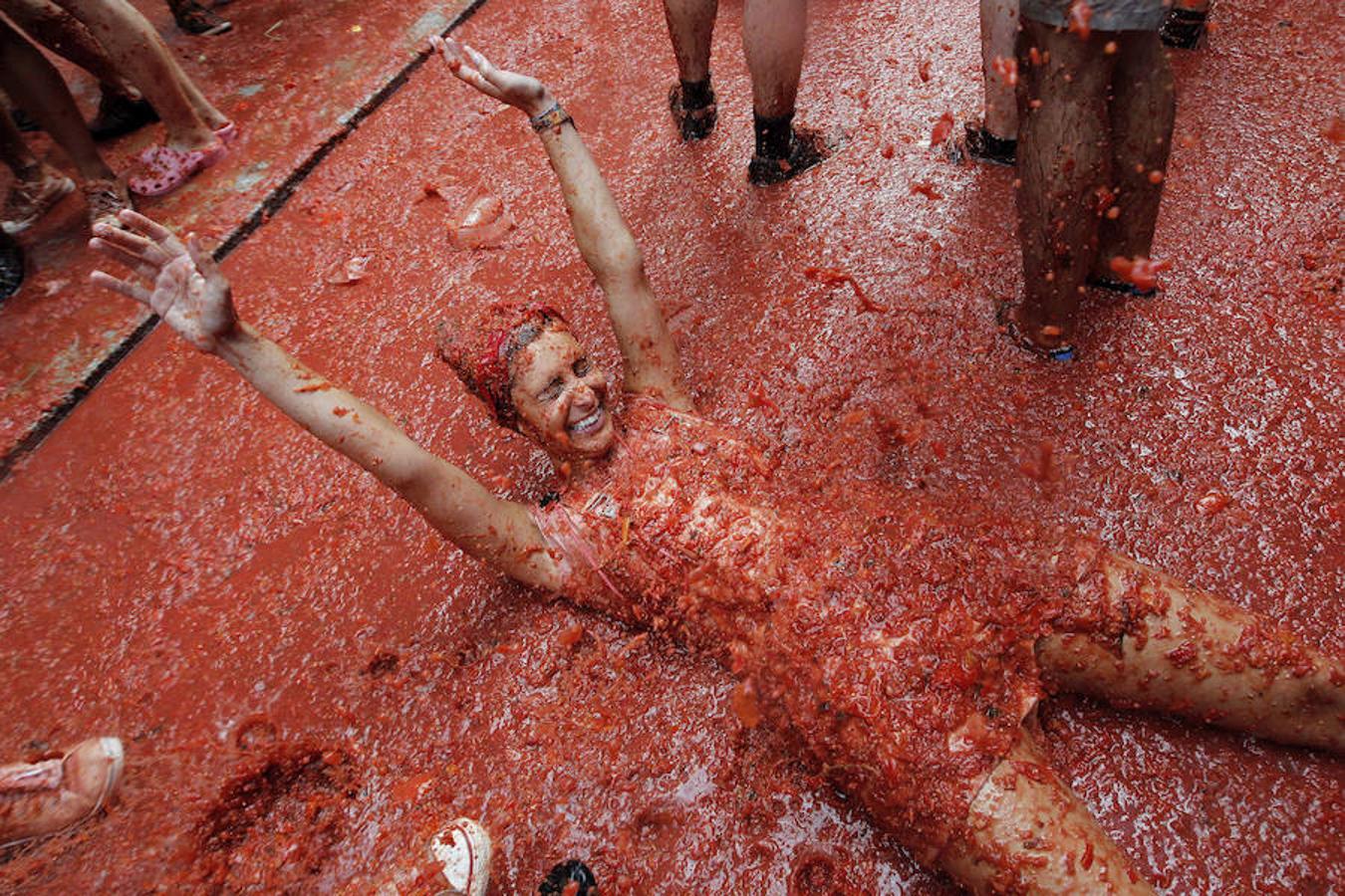 Una turista disfrita los golpes con los tomates.