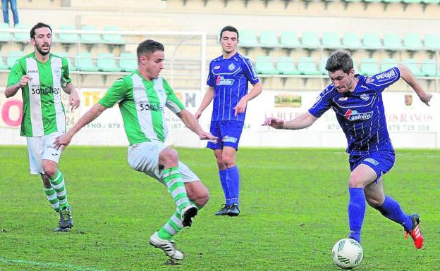 Roberto Levas conduce el balón ante la mirada de Javi Bueno, en el partido que midió al Palencia Cristo Atlético y la Cebrereña en La Balastera.