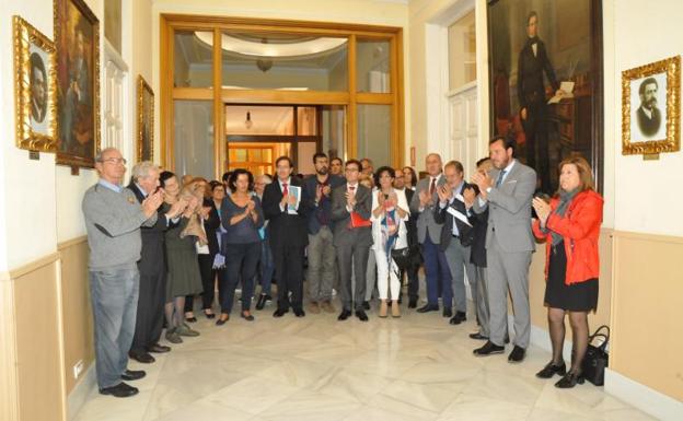 Óscar Puente, representantes de los grupos municipales e invitados al acto aplauden los dos retratos de los alcaldes en uno de los pasillos del Ayuntamiento.