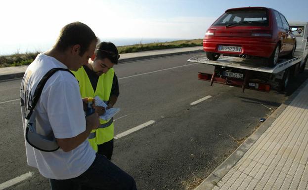 Un hombre arregla los papeles de la grúa tran una avería