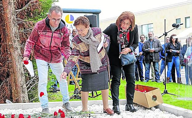 Dos de las asistentes al acto depositan un clavel rojo encima de una de las siluetas del memorial ‘Los 143’. 