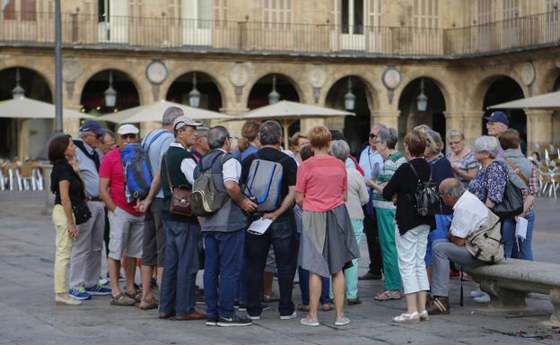 Un grupo de turistas escucha a su guía en la Plaza Mayor.
